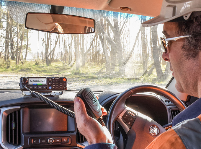 Man holding std mic connected to Tait TM9700 DMR mobile radio