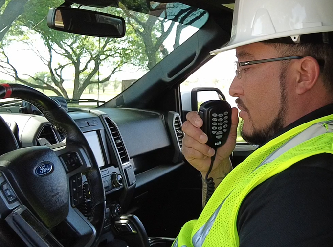 Man holding keypad mic connected to Tait TM9300 DMR mobile radio