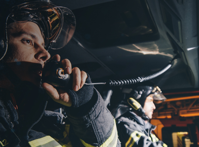 Firefighter holding keypad mic to promote Tait TM9400 P25 mobile radio