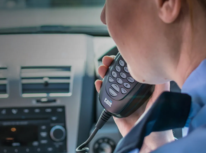 Lady holding keypad mic connected to Tait TM9800 P25 mobile radio